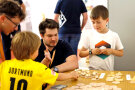 Ein Spiel aus Holzelementen wird zwei Kindern von Mitarbeitern des ALE Oberfranken erklärt